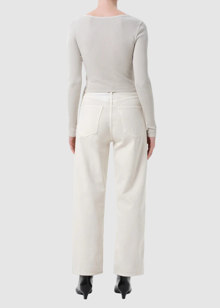 Person wearing a light gray long-sleeve top and white pants on a white background