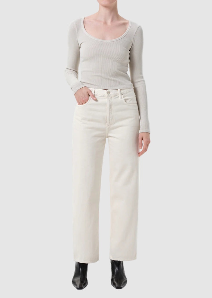 Person wearing a light gray long-sleeve top and white pants on a white background